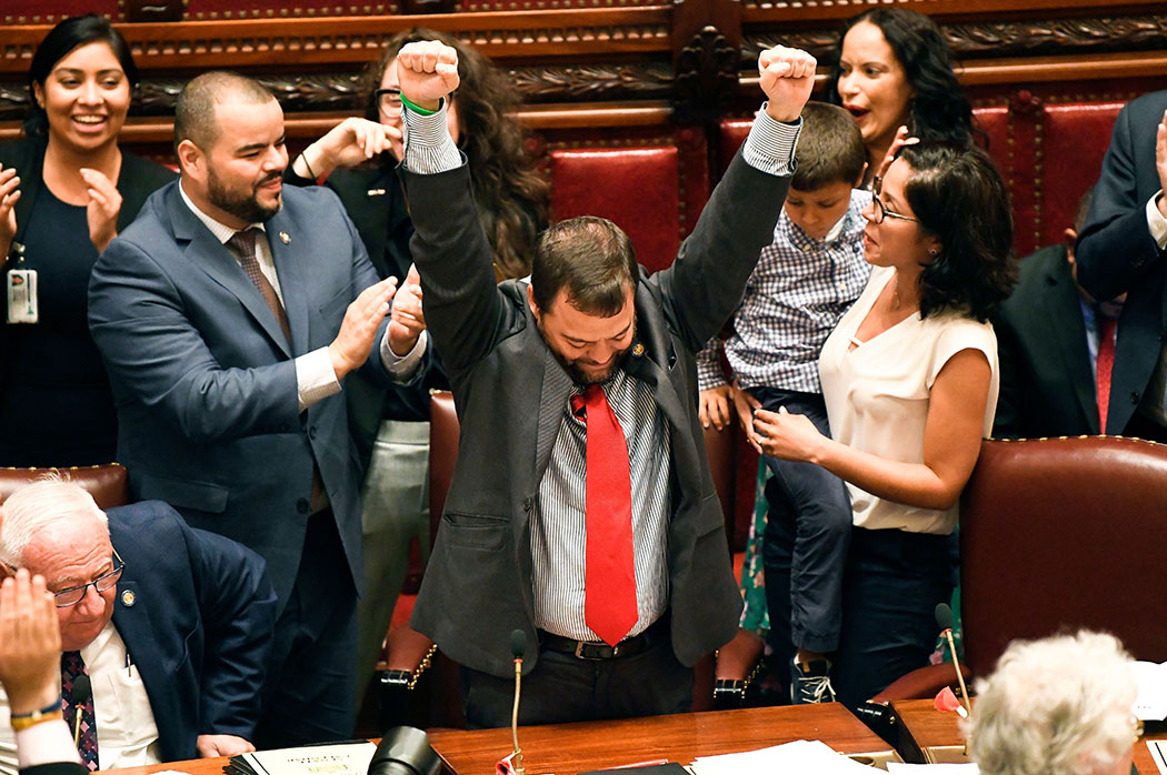 Sen. Luis R. Sepulveda (center) celebrates after the Green Light Bill granting was passed by the state Senate.