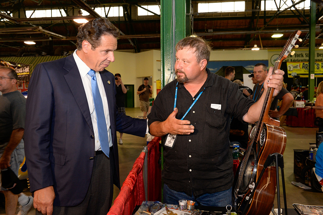 Andrew Cuomo looking at a guitar.