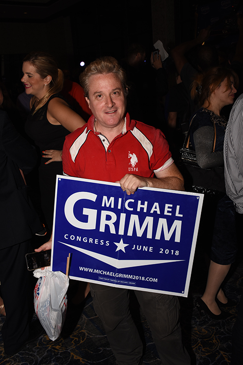 a man holds a Michael Grimm sign.